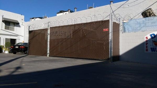 Chain link fence with 3-strand barbed wire, razor ribbon and brown privacy slats