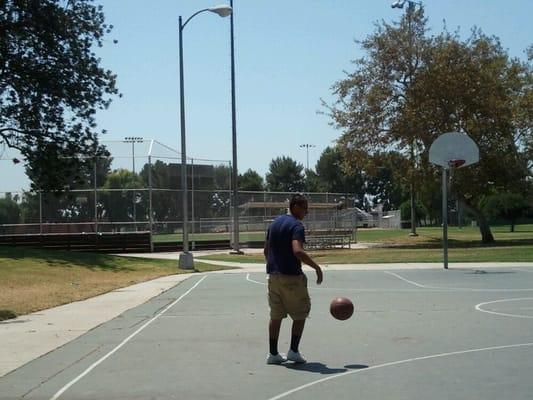 Baseball diamonds are behind the basketball court.