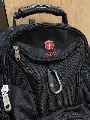 Custom embroidered initials to a travel backpack under the logo.