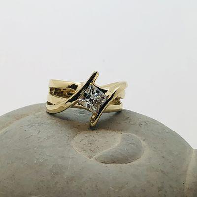 18 karat  ring channel set with a radiant cut diamond.