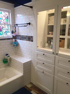 Featured prominently in place of an old shower stall is a linen cabinet with drawers and shelves that we custom-built