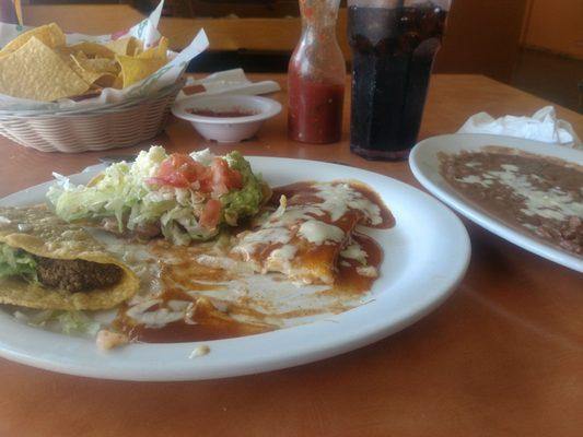 Taco, Chalupa, Cheese Enchilada with a side of refried beans. Free chips and salsa in the background.