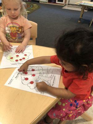 Jr. Preschool using fine motor skills to enhance their understanding of number correspondence.