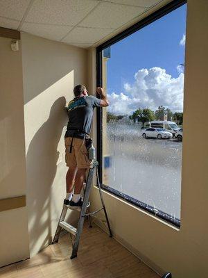 Jim Shelton cleaning glass after removing old film, prepping for installation of new film.