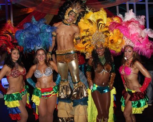 Stilter with energetic Samba dancers