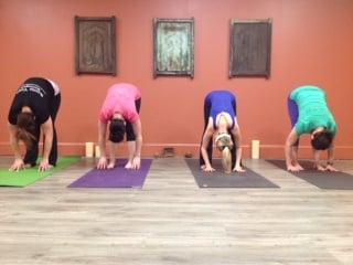 Roots Students in uttanasana (forward fold) part of a Sun Salutiaton.