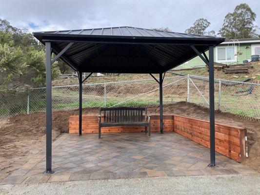 Installation of beautiful pavers , with a redwood retaining wall  , and a black aluminum gazebo.