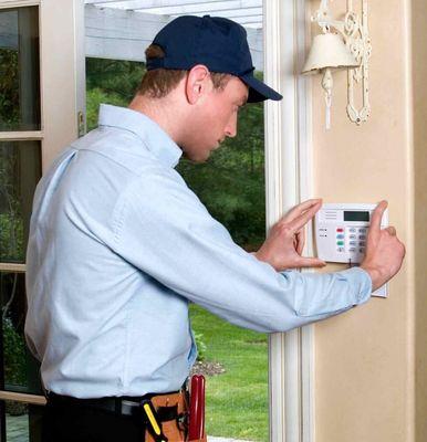 Technician installing an alarm system at a residential property