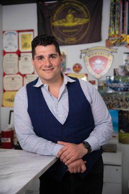 GoBeRewarded CEO, Aaron Gobidas, in front of his Marine Corp memorabilia and Jiu Jitsu medals.