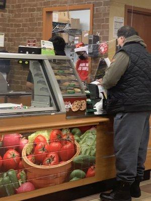 Photo of employees on cell phones while multiple customers wait in line.