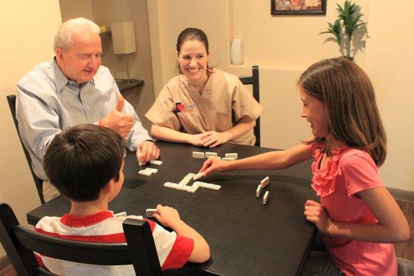 Caring Senior Service caregiver playing games with a client and his family