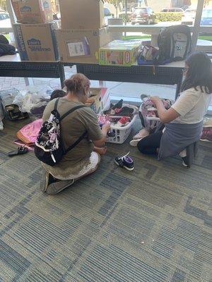 Our young volunteer is eager to help a family with shoes!