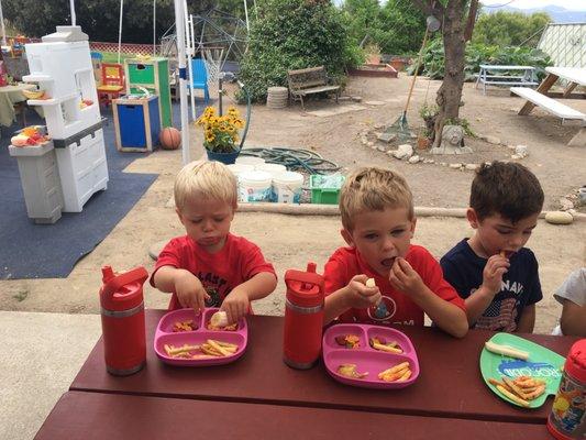 Snack time! In the background you can see buckets that the kids take bottles and fill them with water and love watering plants with.