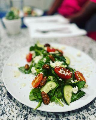 Spinach goat cheese salad topped with candy pecans cucumber and tomato