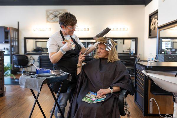 Hairstylist putting in a highlight.