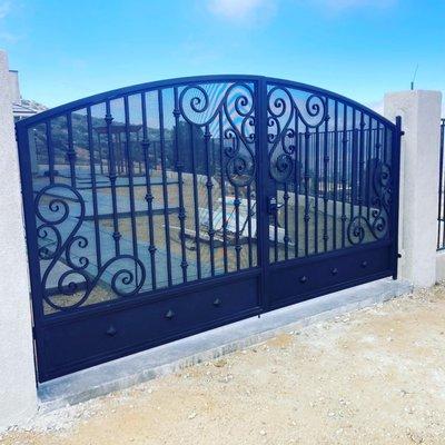 Decorative iron gate with custom scroll design, perforated sheet backing, toe kick and double lock box for handle and dead bolt.