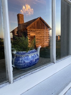 Sunset view of teapots in the window with the cookhouse in the reflection.