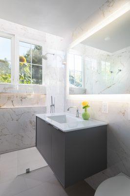 Polished marble tile and the large window add incredible light and spaciousness to this new modern bathroom.