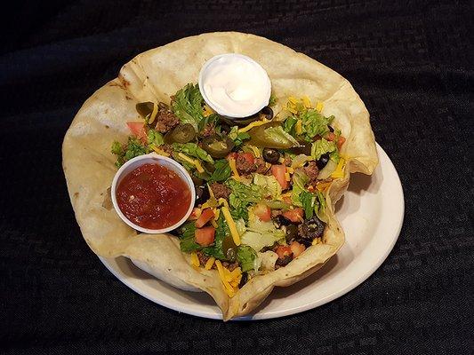 Incredibly delicious Taco Salad featuring a deep-filled crust of Taco Meat, shredded Cheddar Cheese, Black Olive, Jalapeno, and Tomato.