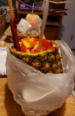 Pineapple with chili powder and chamoy, rainbow snow cone behind.