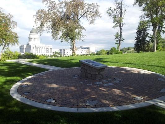 Original stones embedded in circular courtyard where tower once stood; bench overlooking capital building