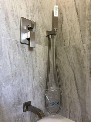 Complete bathroom renovation including traditional three faucet system plumbing converted into one handle and hand shower addition