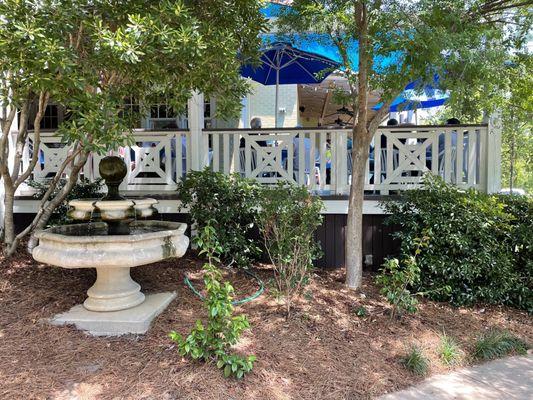 The covered patio wraps around the building and is surrounded by lush landscaping.