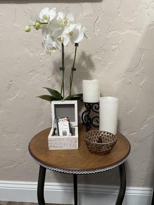 Gorgeous white orchid and candles on a circular wooden table with rhinestone around the table edge and business cards.