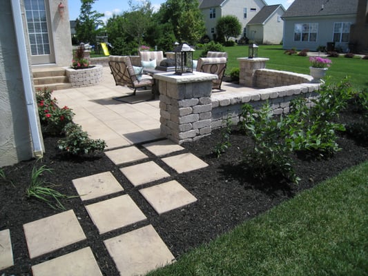 Outdoor living area with hardscape elements including patio, walls, pillars, planters, steps, and a garden path.