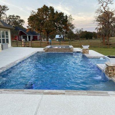 Pool and spa with travertine coping and fire bowls for a simply picturesque outdoor living area.