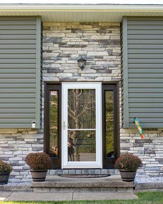 Entry surrounded by stone veneer and premium vinyl siding