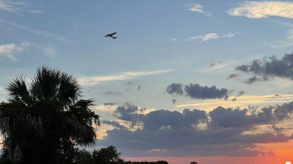 I sunset, clouds, and a fixed wing plane.