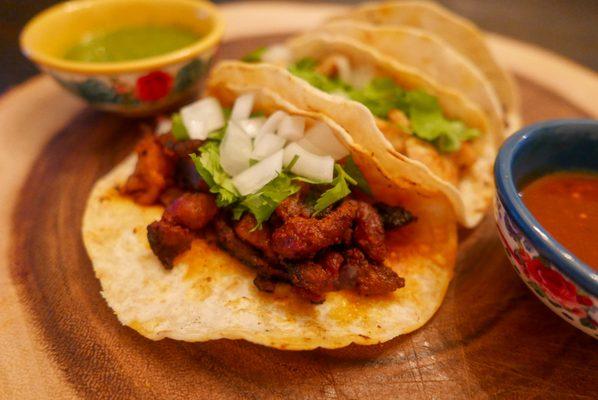 Tacos al Pastor. Mexican roasted pork, marinated with guajillo chiles served on a corn tortilla with Cilantro & Onions. (may be spicy for so