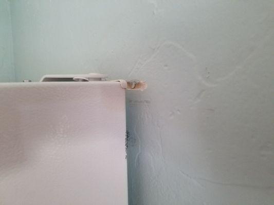 Damage to kitchen wall apparently by fridge.