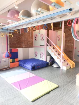 Our Tribeca Sensory gym space has a "castle" with a slide, a rock wall, a zip line, and plenty of sensory swings!