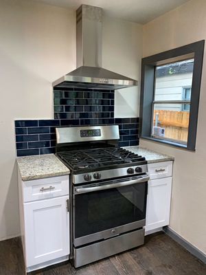 New granite and cabinets with navy subway tile.