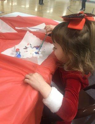 My toddler painting her first ornament at the POMS Winter Social the mother of the kid's I nanny invited us to! !