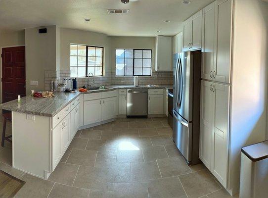 kitchen remodel with shaker white cabinets, new peninsula, tile flooring, new appliances, backsplash and paint