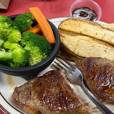 New York steak and steamed veggies along with potato wedges