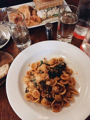 Front: orecchiette with pork bolognese, back: house turkey sandwich with chips