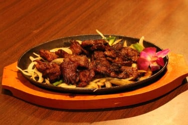 Mongolian Beef sliced tender beef barbecued with flavorful brown sauce on bed of garden onion