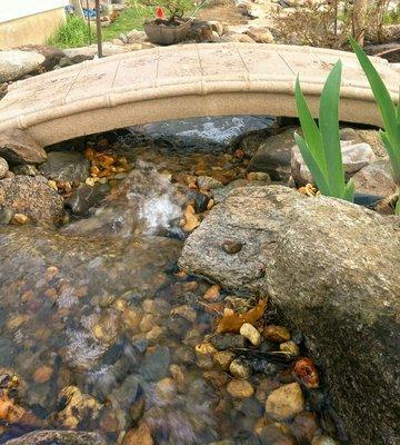 A stone bridge offers cool passage over the newly installed creek