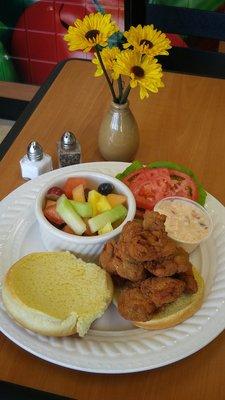 Fried oyster po boy sandwich with a fruit cup.