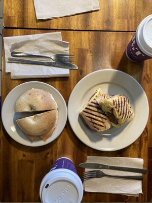 Photo of food and coffee on table. Bagel with cream cheese and lox on left and gluten free breakfast wrap on right.