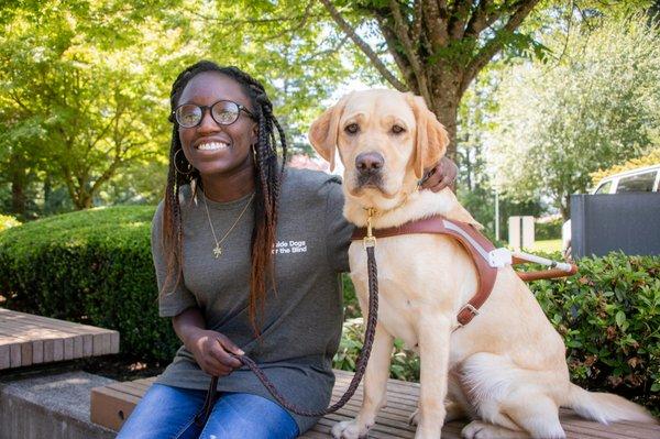 Youth client seated beside a yellow lab guide dog.