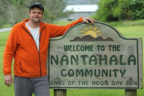 Eric Mason standing by the welcoming sign for the Nantahala Community.