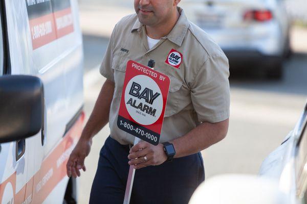 Bay Alarm technician with sign.