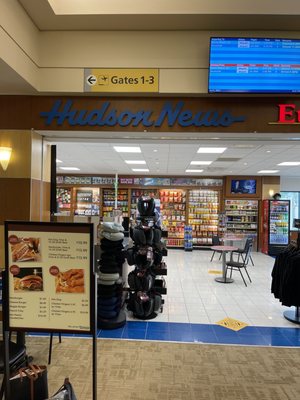 Entrance and located at the top of the escalator.