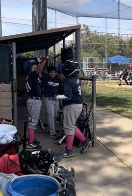 Team congratulating my boy on a good run when he returns to the dugout.