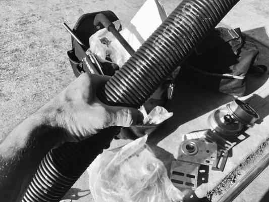 Replacing the broken, old rusted springs of our garage door opener system with a safer, large central over door spring.